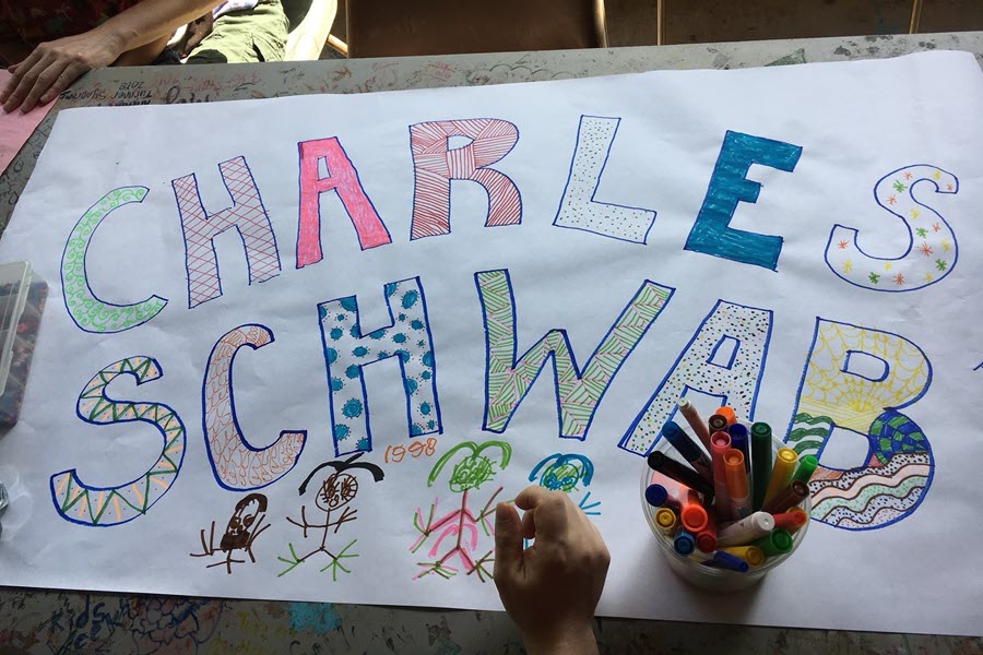 Campers decorate a banner to thank Charles Schwab.