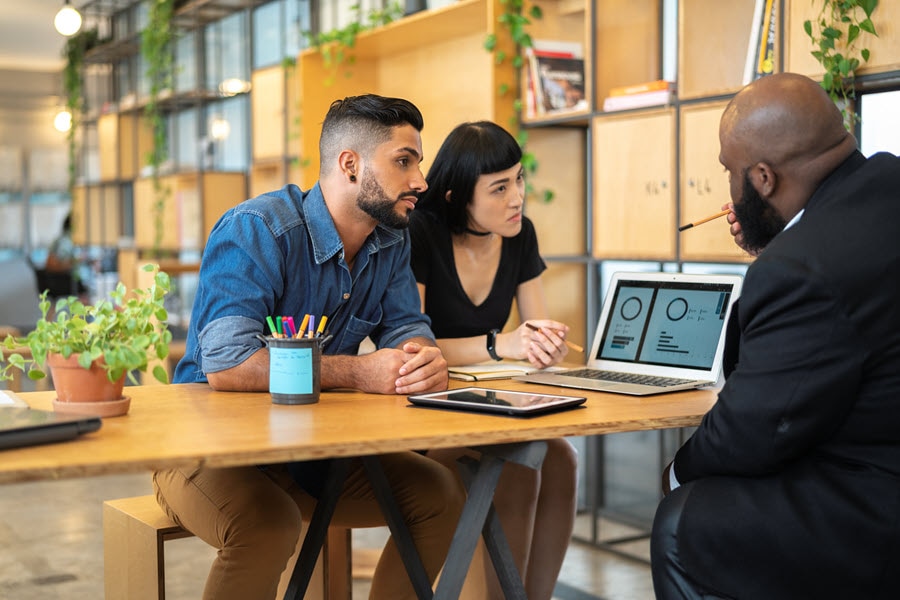 Young couple meeting with a man at a table with a laptop